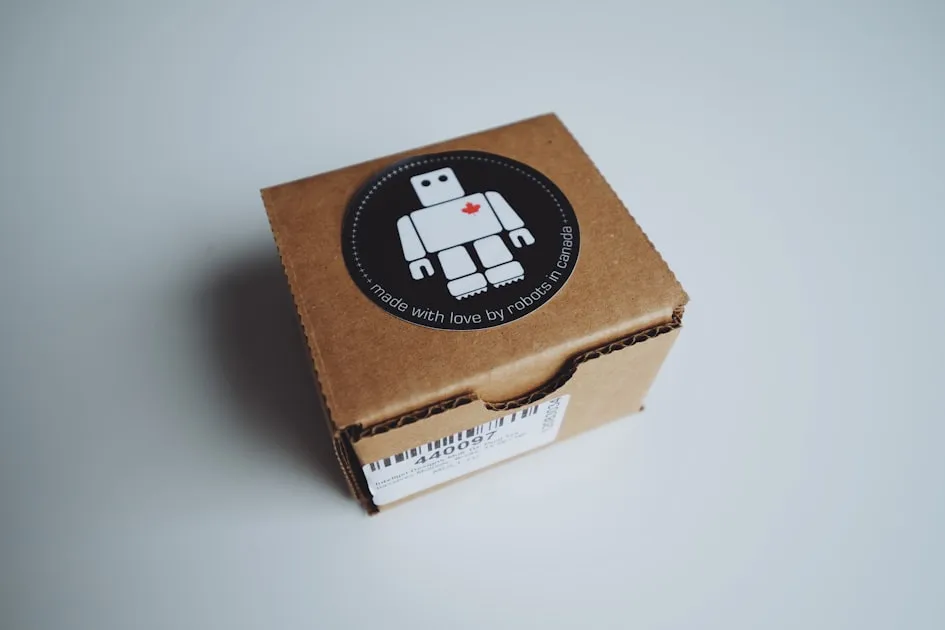 Small cardboard box with a robot sticker on top — Gửi Hàng Tại Vinhomes Ocean Park - So Sánh VP, GHN, GHTK