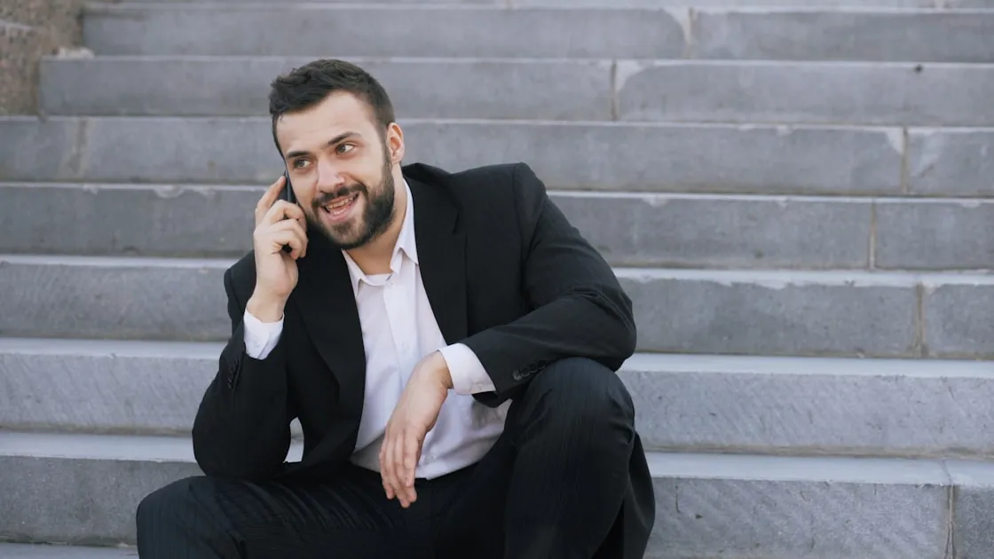 Young bearded business man talking on cell phone making deals sitting on stairs in the street — Review Khách Hàng Thực Tế ...