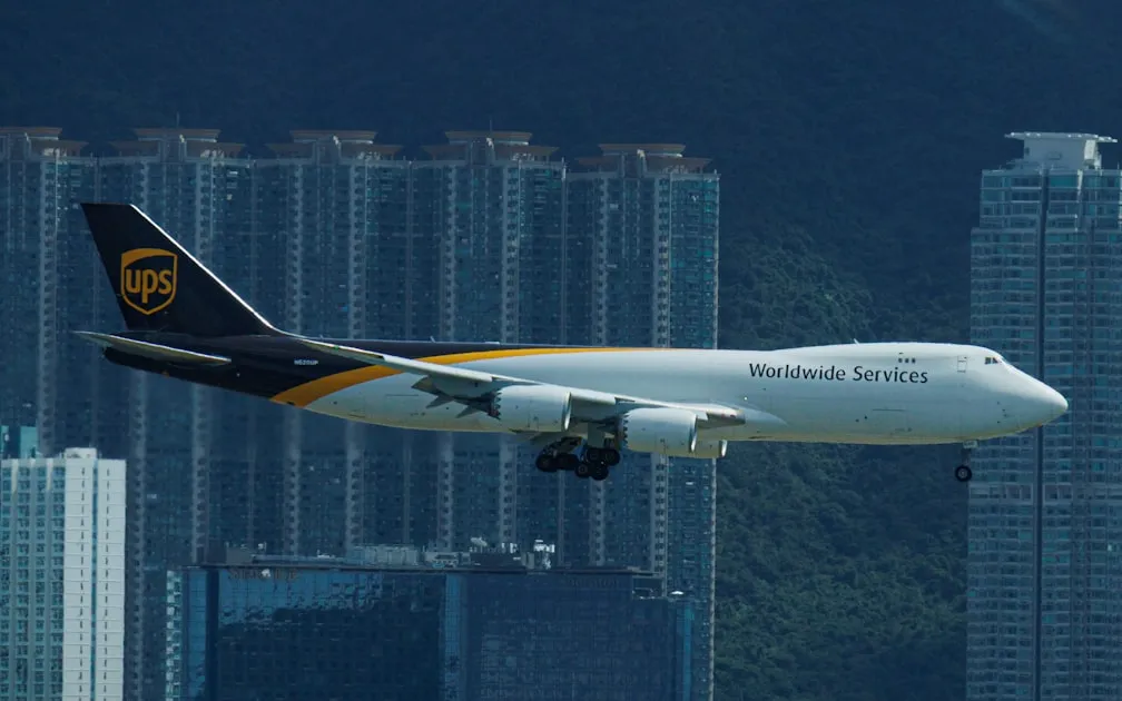 A ups cargo plane flies over city buildings — So Sánh Viettel Post vs GHN vs GHTK - Hãng Nào Tốt Nhất?